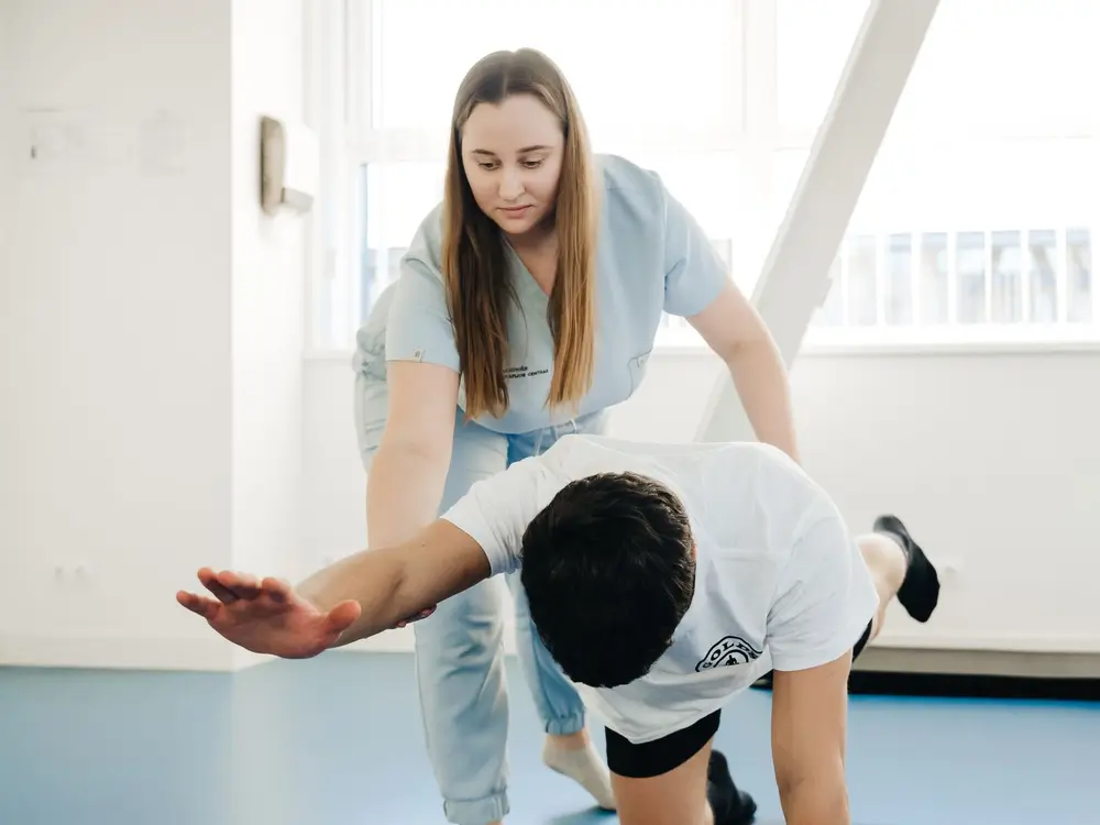 Kinesitherapeut begeleidt een oefening in de praktijk